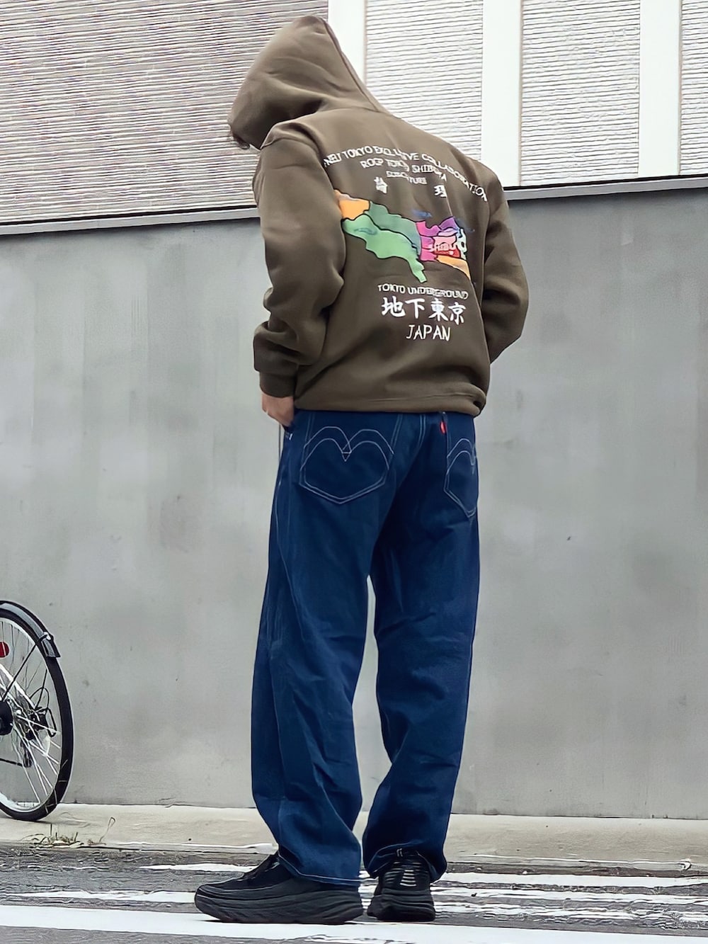 ブルー系のデニムパンツ、グリーン系のパーカー、ブラック系のスニーカーを着用したメンズの夏コーディネートの2枚目の写真