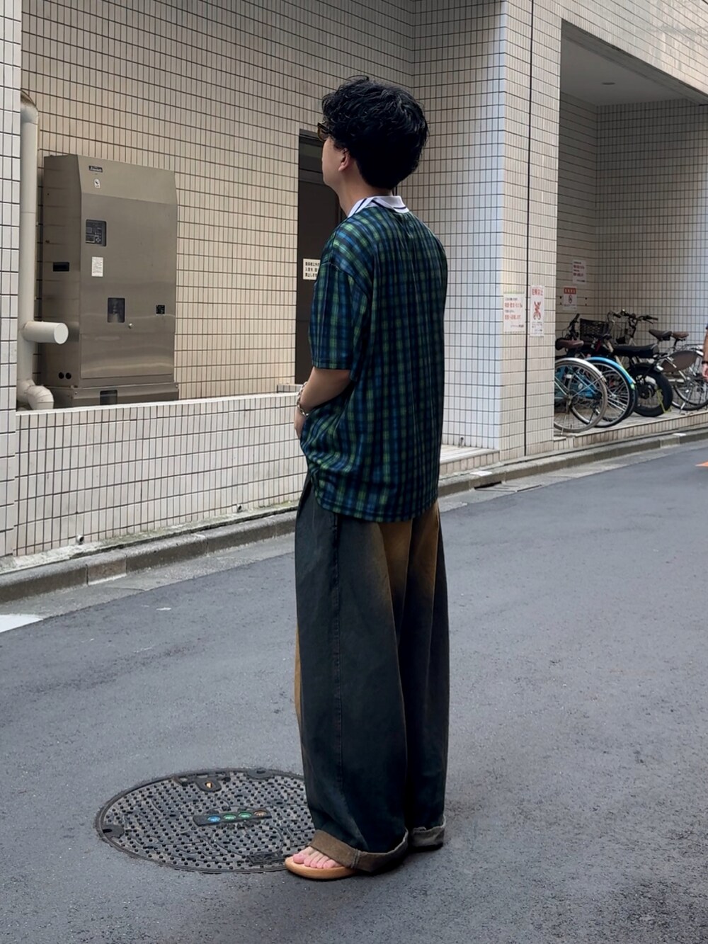 ブルー系のデニムパンツ、ブラック系のトップス、ベージュ系のサンダルを着用したメンズの夏コーディネートの2枚目の写真