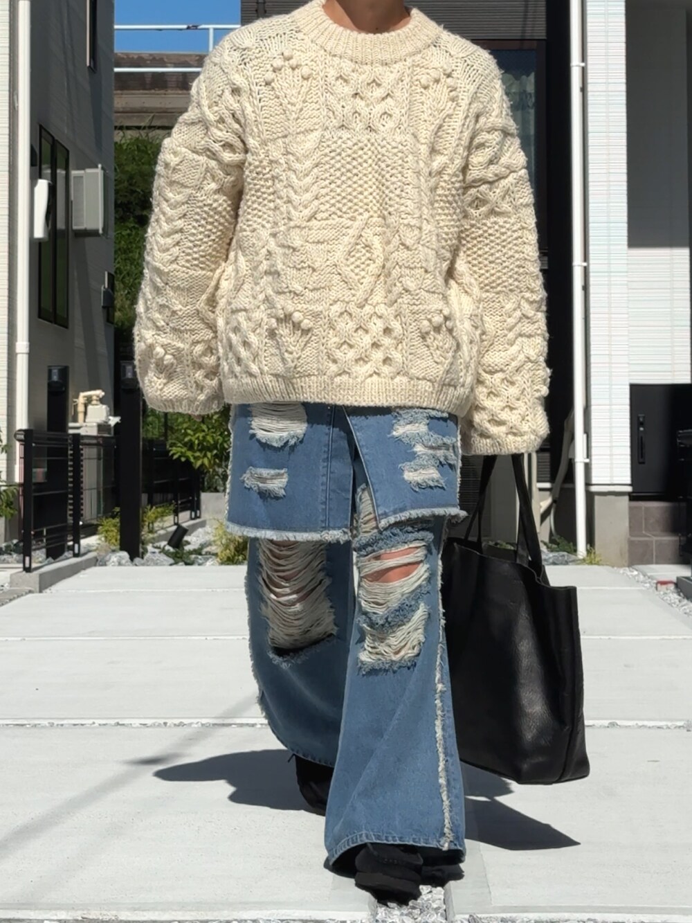 ブルー系のデニムパンツ、ホワイト系のニット/セーター、ブラック系のトートバッグを着用したメンズの秋コーディネートの4枚目の写真