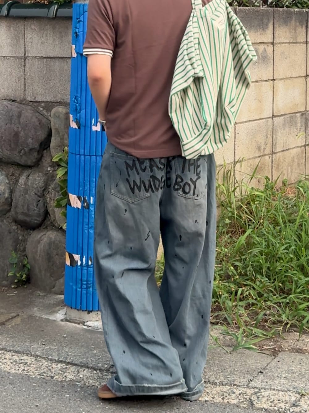 ブラック系のデニムパンツ、ブラウン系のポロシャツ、ブラウン系のスニーカーを着用したメンズの夏コーディネートの2枚目の写真