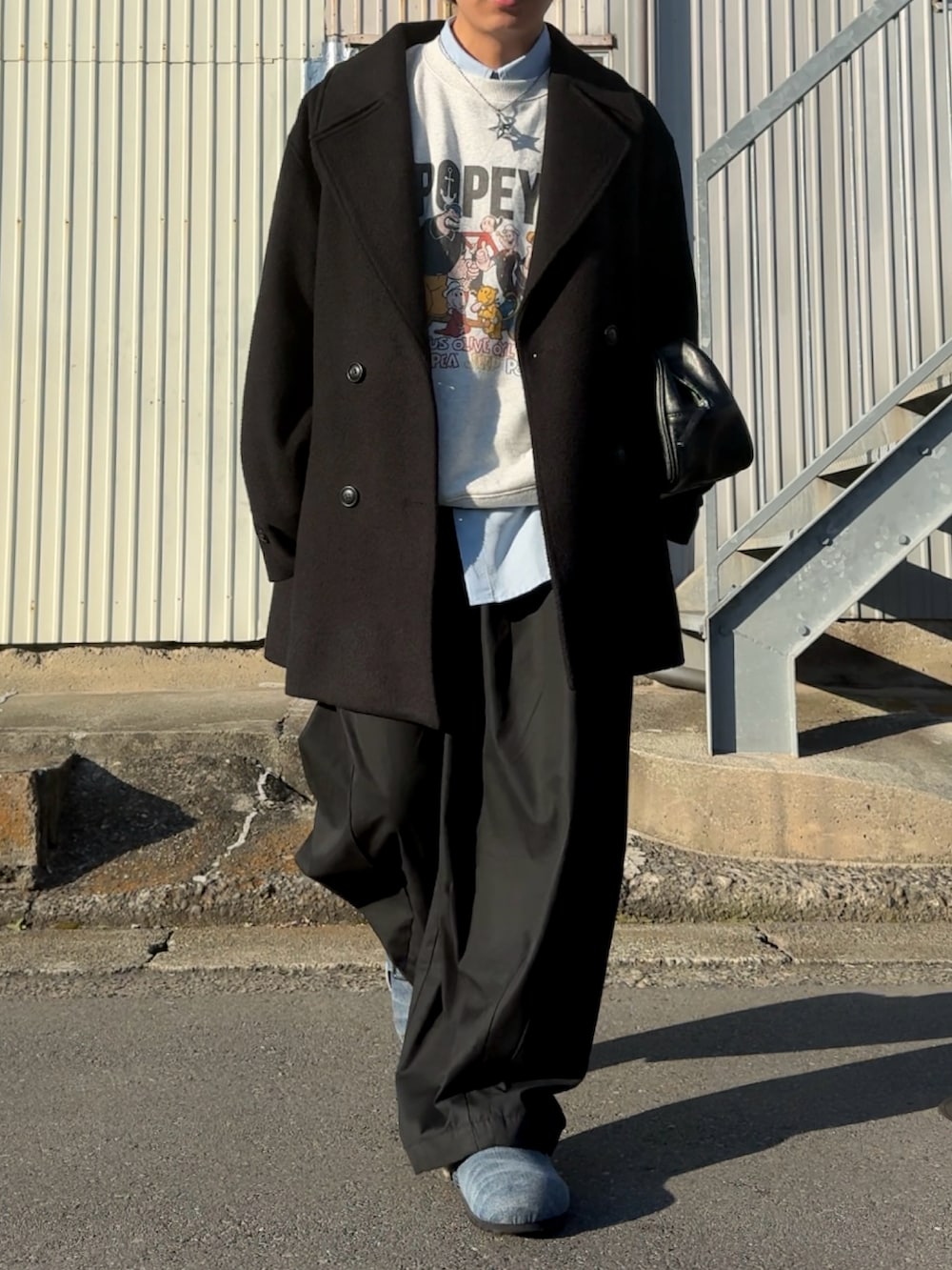 ブルー系のスラックス、レッド系のボストンバッグ、グレー系のスウェットを着用したメンズの冬コーディネートの3枚目の写真