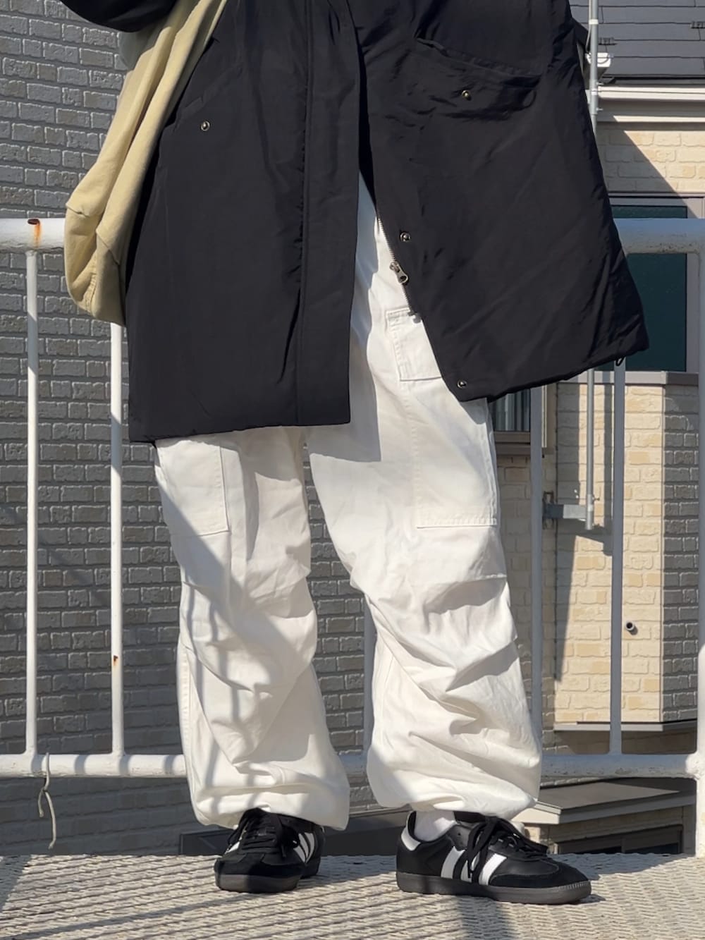 ブラック系のスニーカー、ホワイト系のカーゴパンツ、ブラック系のジャケット/アウターを着用したメンズの冬コーディネートの2枚目の写真