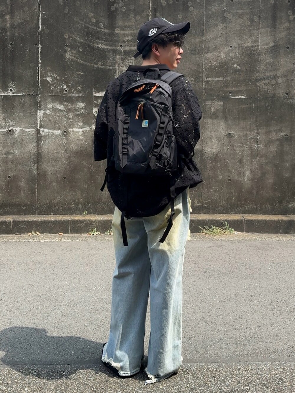 ブラック系のポロシャツ、ブラック系のバックパック/リュック、ブルー系のデニムパンツを着用したメンズの秋コーディネートの3枚目の写真