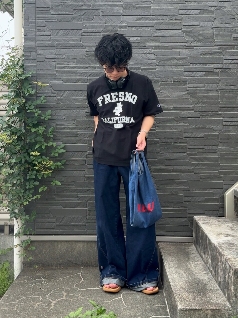 ブラック系のTシャツ/カットソー、ブルー系のデニムパンツ、ベージュ系のサンダルを着用したメンズの夏コーディネートの2枚目の写真