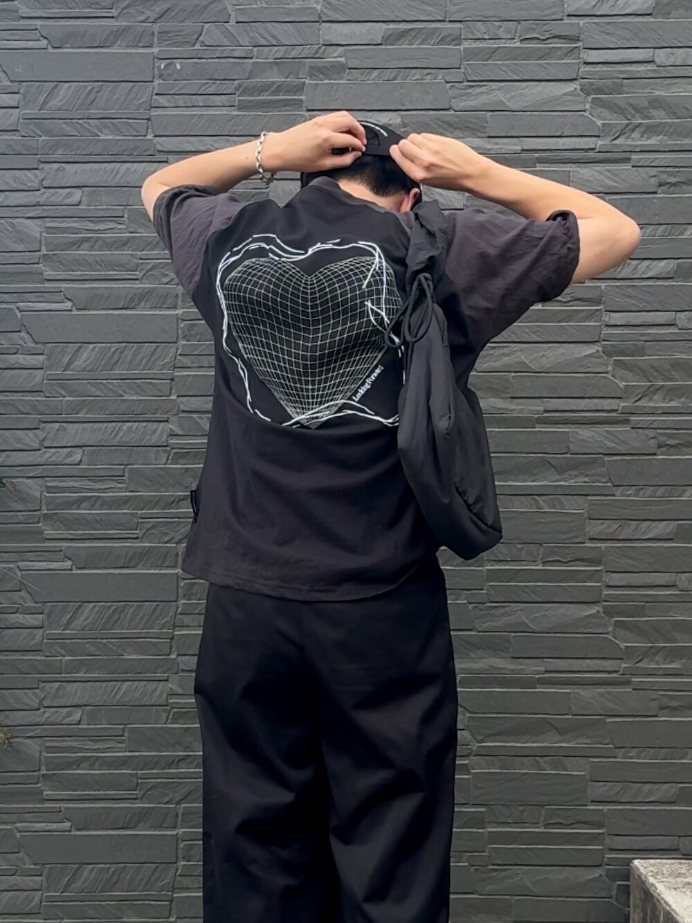 ブラック系のTシャツ/カットソー、ブラック系のスラックス、ブラック系のスニーカーを着用したメンズの夏コーディネートの3枚目の写真