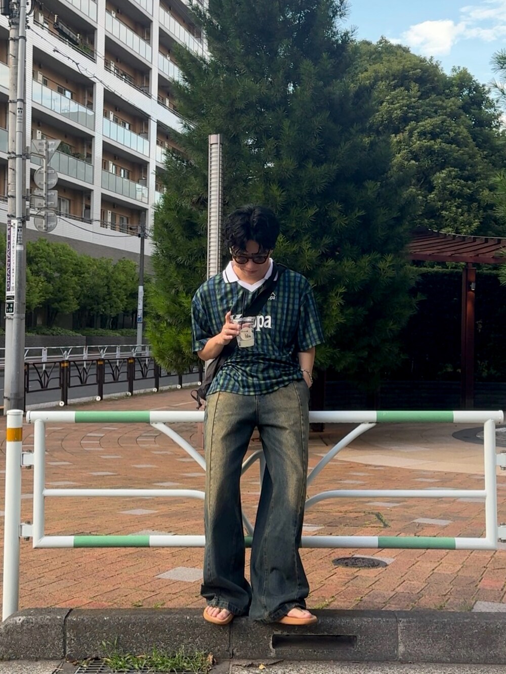 ブルー系のデニムパンツ、ブラック系のトップス、ベージュ系のサンダルを着用したメンズの夏コーディネートの2枚目の写真