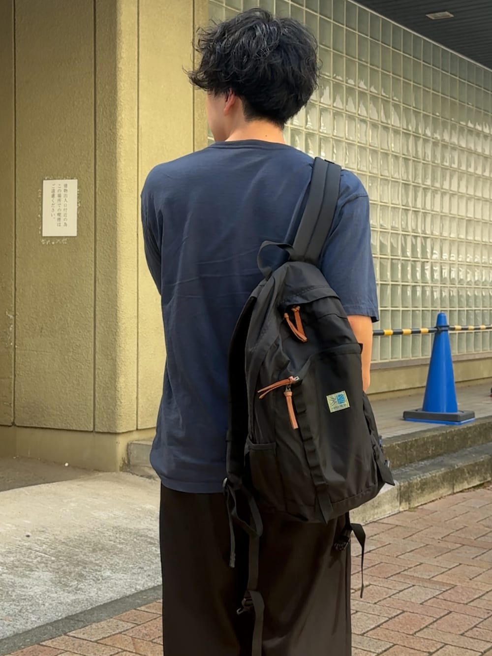 ブルー系のTシャツ/カットソー、ブラック系のスラックス、ブラック系のバックパック/リュックを着用したメンズの秋コーディネートの2枚目の写真