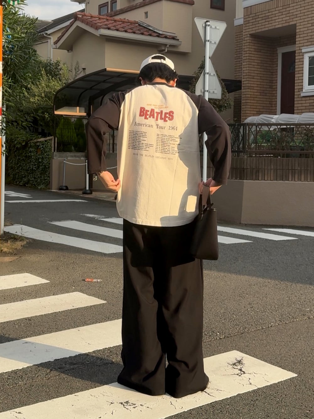 ブラック系のスラックス、ブラック系のTシャツ/カットソー、ブラック系のトートバッグを着用したメンズの秋コーディネートの2枚目の写真