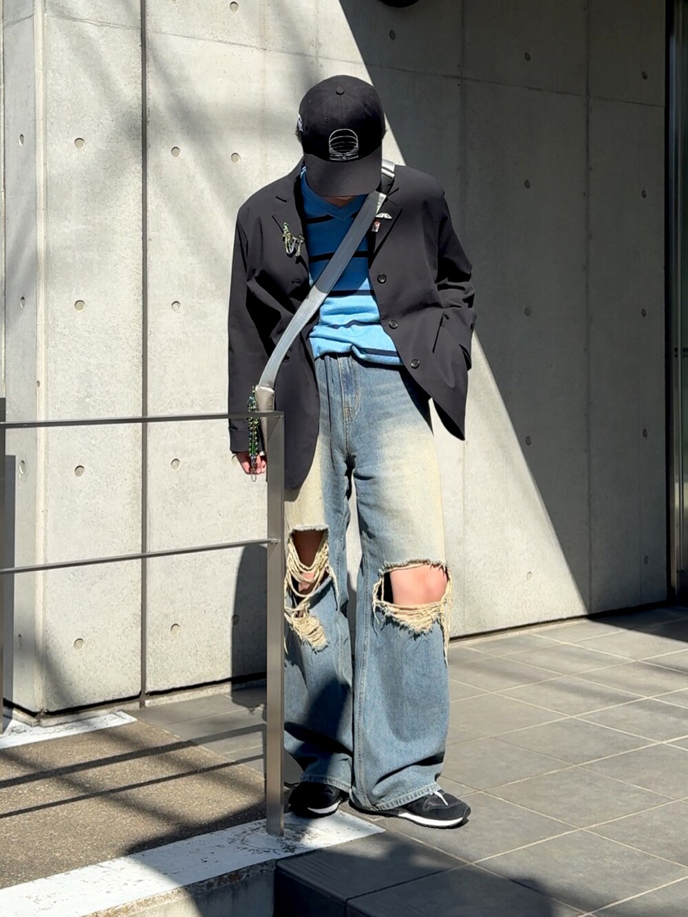 ブラック系のスニーカー、ブルー系のデニムパンツ、シルバー系のバッグを着用したメンズの春コーディネートの3枚目の写真