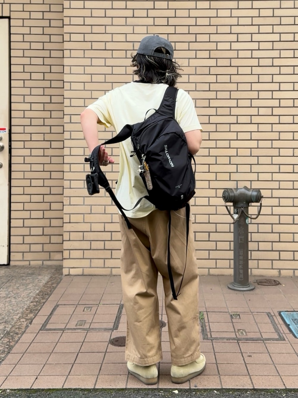 ブラック系のバックパック/リュック、ベージュ系のチノパンツ、ベージュ系のスニーカーを着用したメンズの春コーディネートの2枚目の写真