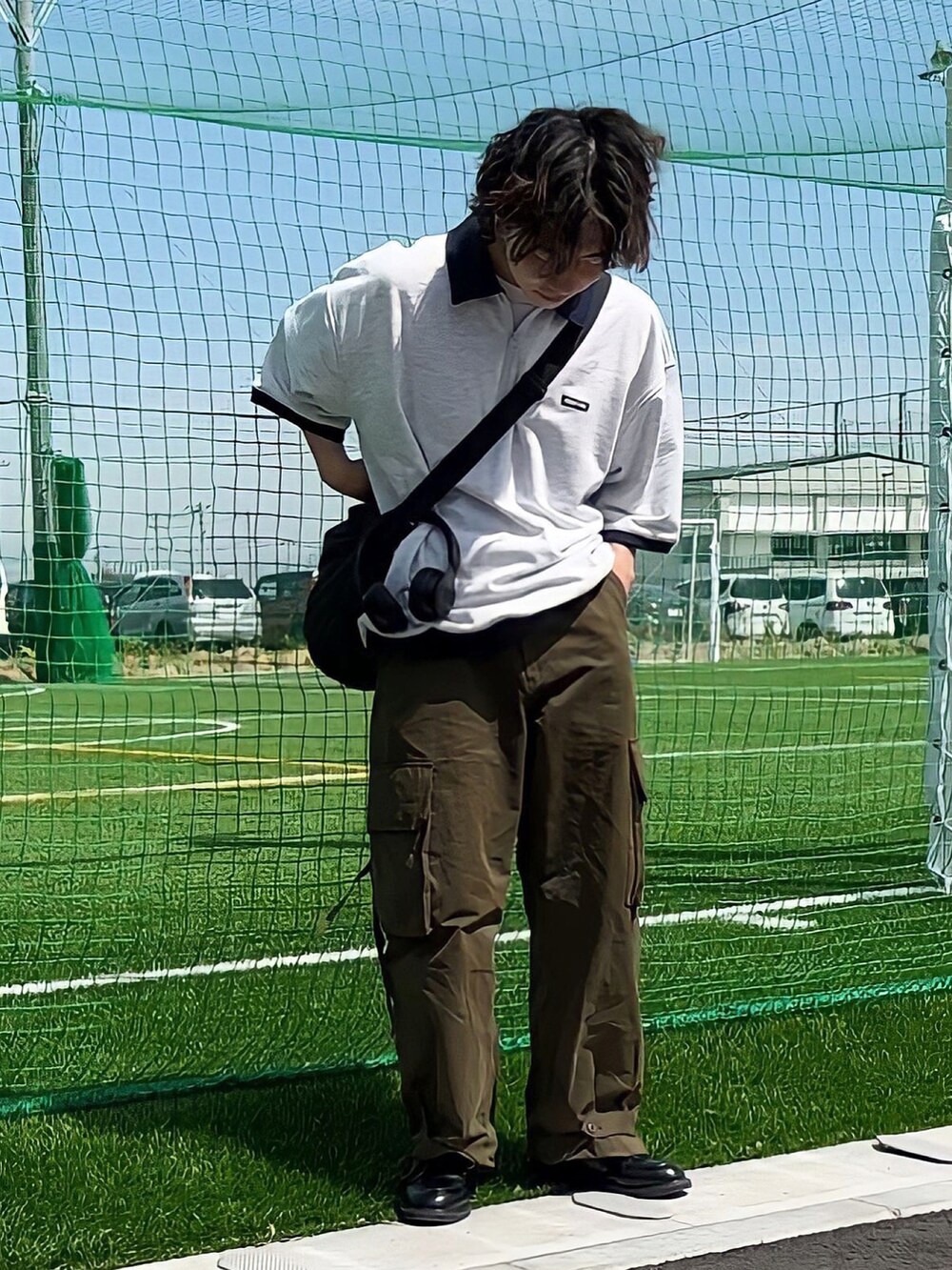 グリーン系のカーゴパンツ、ブラック系のバッグ、ブラック系のドレスシューズを着用したメンズの春コーディネートの2枚目の写真
