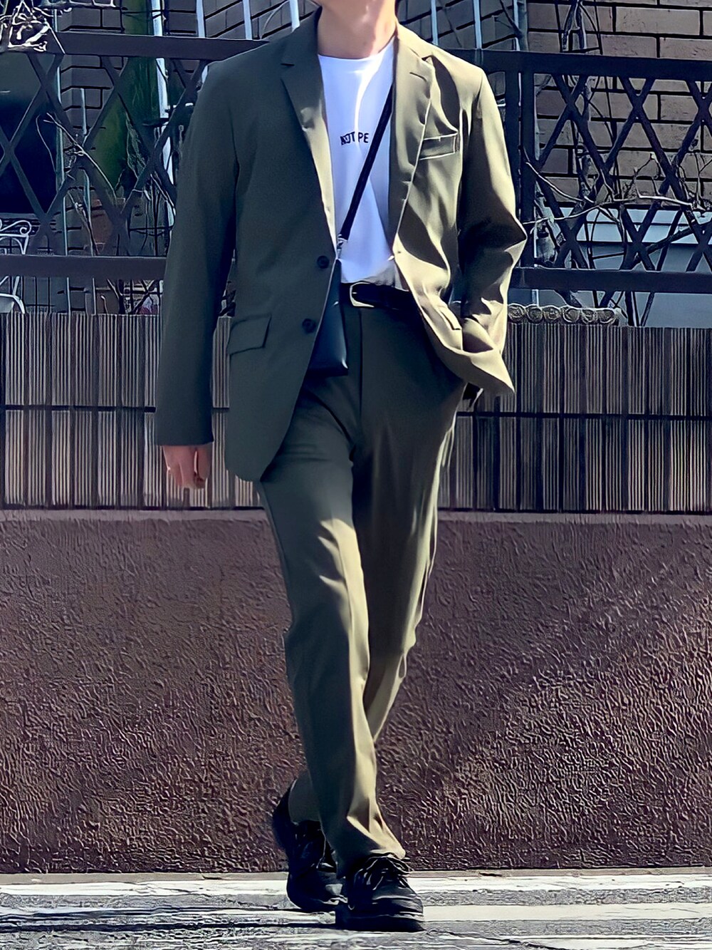 グリーン系のセットアップ、ホワイト系のTシャツ/カットソー、ブラック系のショルダーバッグを着用したメンズの冬コーディネートの3枚目の写真