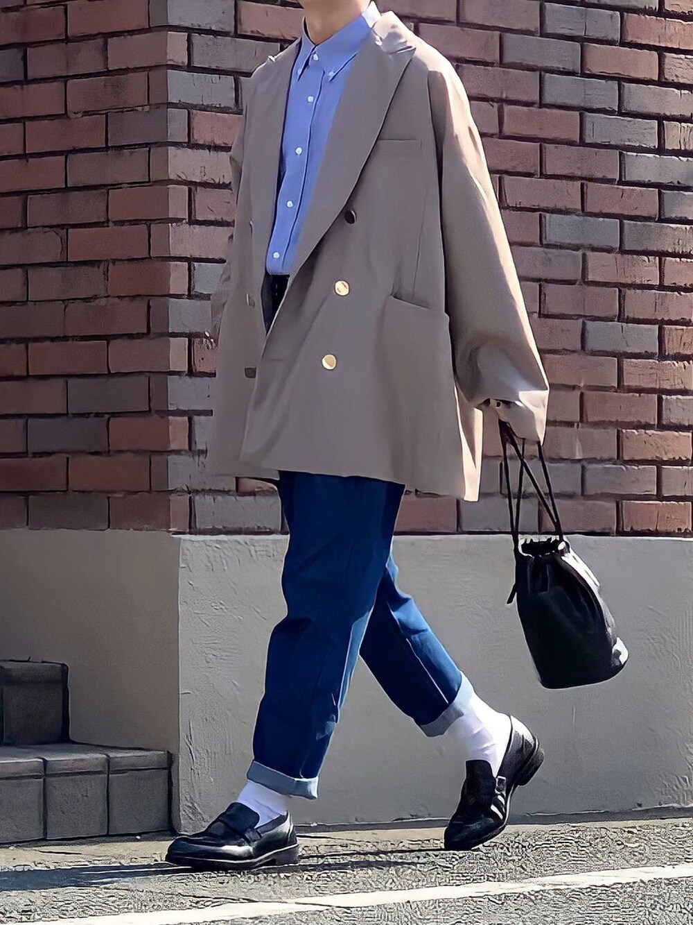 ブラック系のハンドバッグ、ブルー系のデニムパンツ、ブラック系のローファーを着用したメンズの秋コーディネートの2枚目の写真