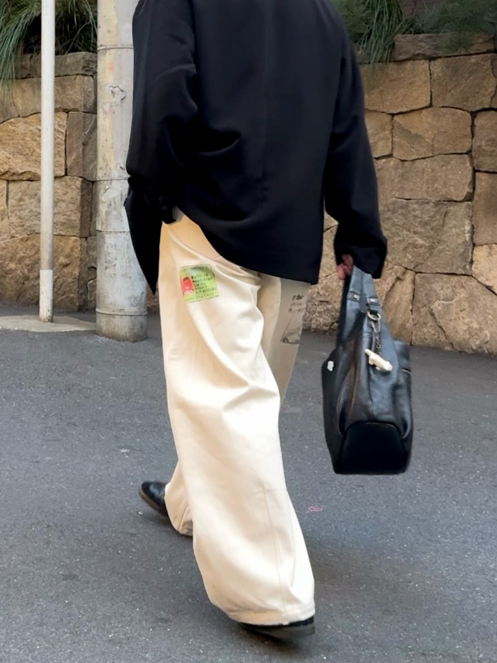 ブラック系のテーラードジャケット、ホワイト系のその他パンツ、ブラック系のスニーカーを着用したメンズの春コーディネートの3枚目の写真