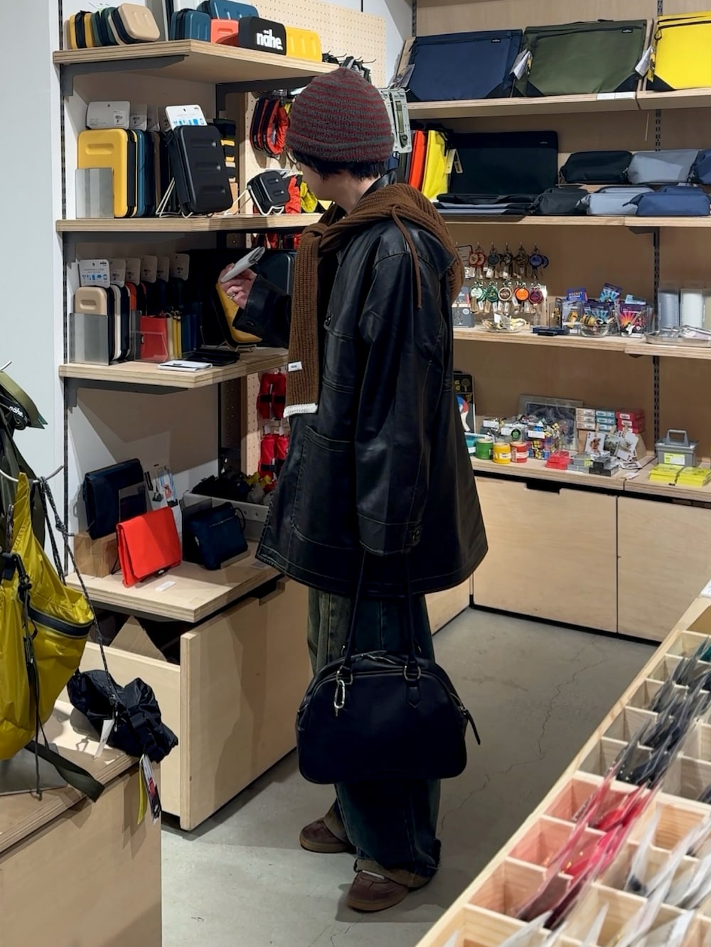 ブラック系のカバーオール、ブルー系のデニムパンツ、レッド系のボストンバッグを着用したメンズの冬コーディネートの2枚目の写真