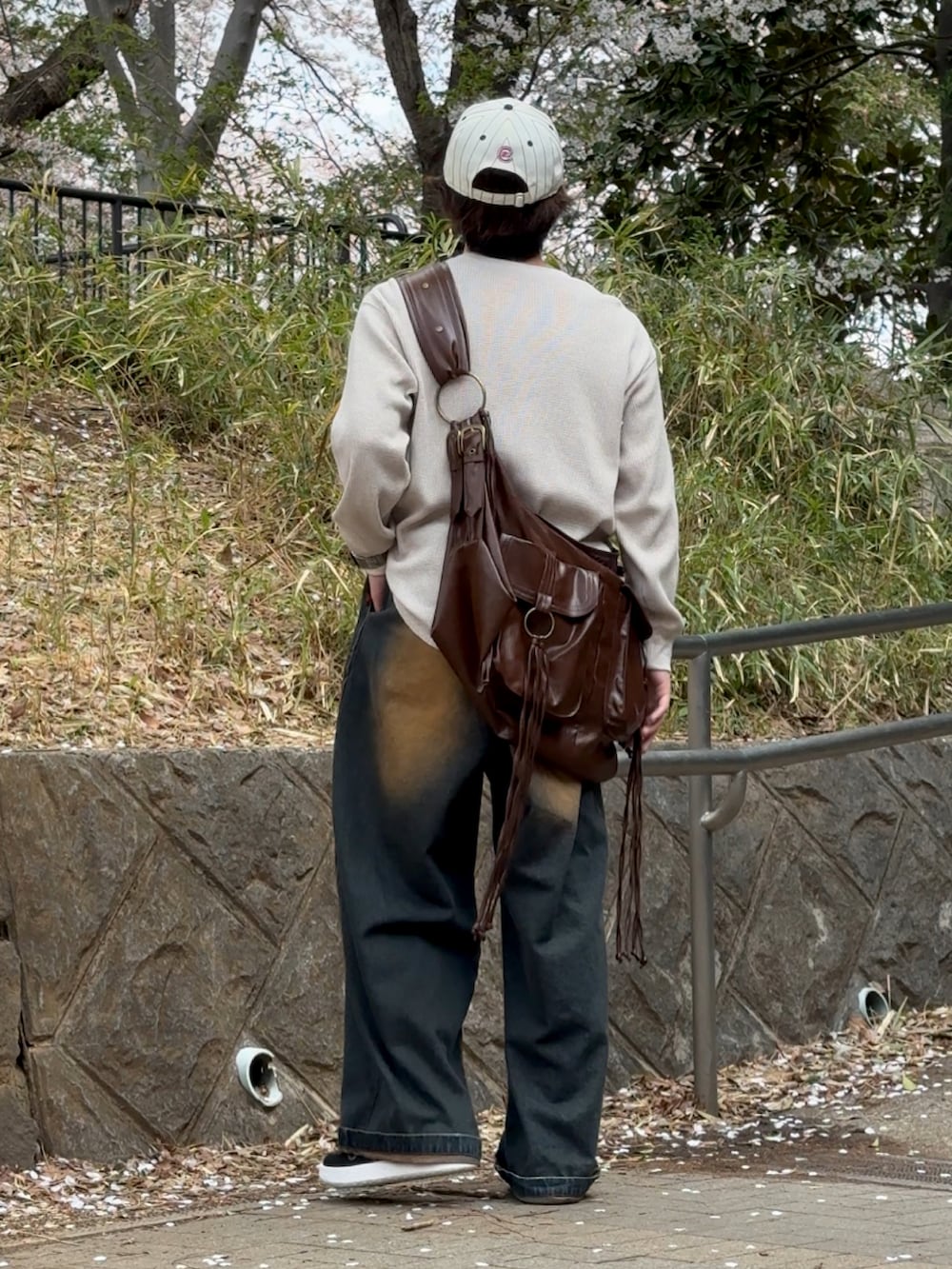 ブルー系のデニムパンツ、ベージュ系のTシャツ/カットソー、ブラウン系のショルダーバッグを着用したメンズの春コーディネートの2枚目の写真