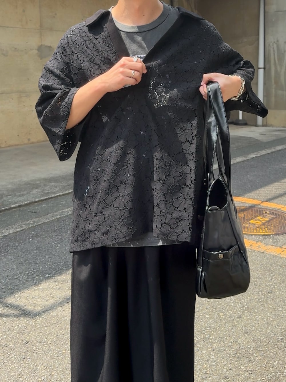 ブラック系のポロシャツ、ブラック系のショルダーバッグ、ブラック系のスラックスを着用したメンズの夏コーディネートの3枚目の写真