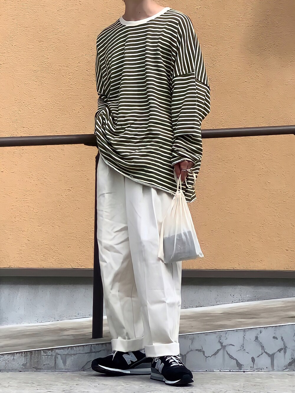 ホワイト系のチノパンツ、ブラック系のTシャツ/カットソー、ブラック系のスニーカーを着用したメンズの夏コーディネートの2枚目の写真