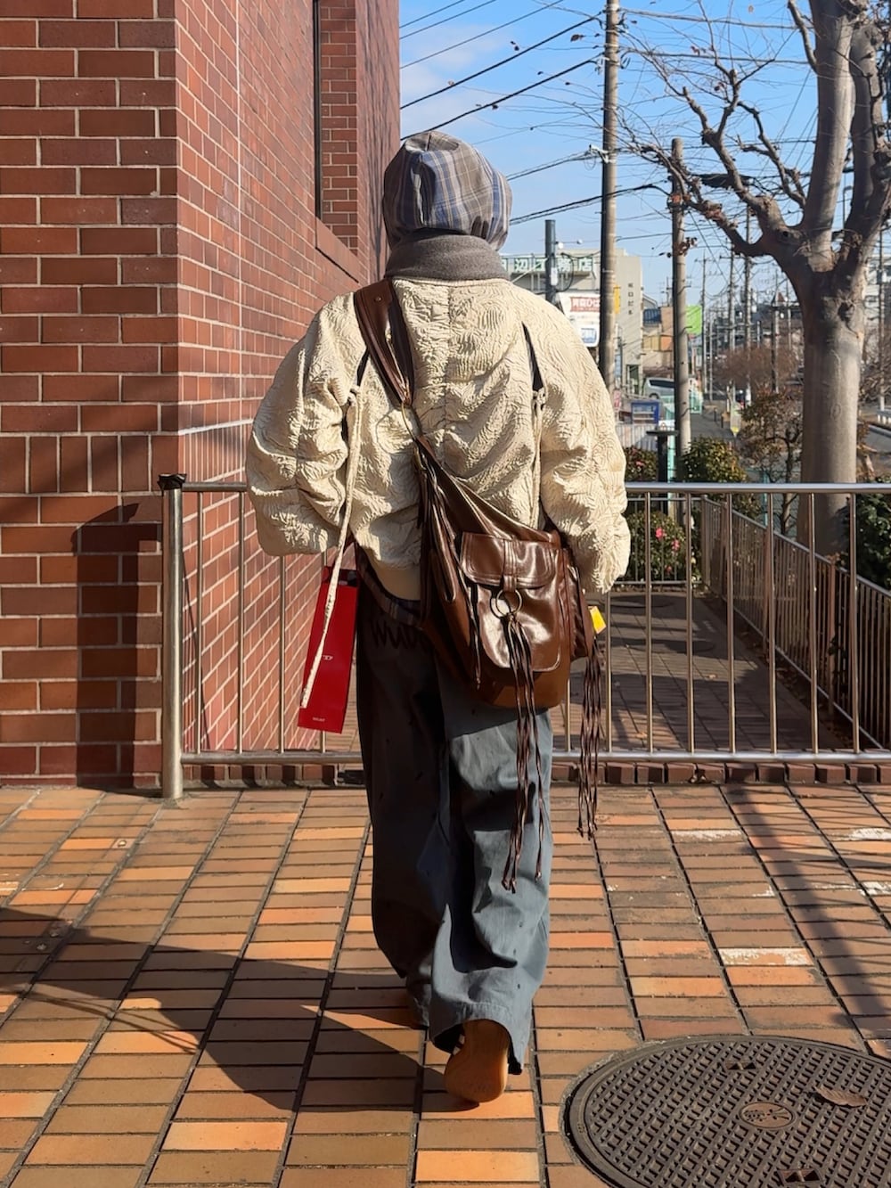 ブラック系のデニムパンツ、ブラウン系のスニーカー、ブラウン系のショルダーバッグを着用したメンズの冬コーディネートの3枚目の写真
