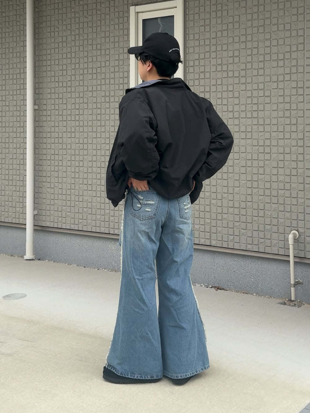 ブルー系のデニムパンツ、ブラック系のTシャツ/カットソー、ベージュ系のブルゾンを着用したメンズの秋コーディネートの3枚目の写真