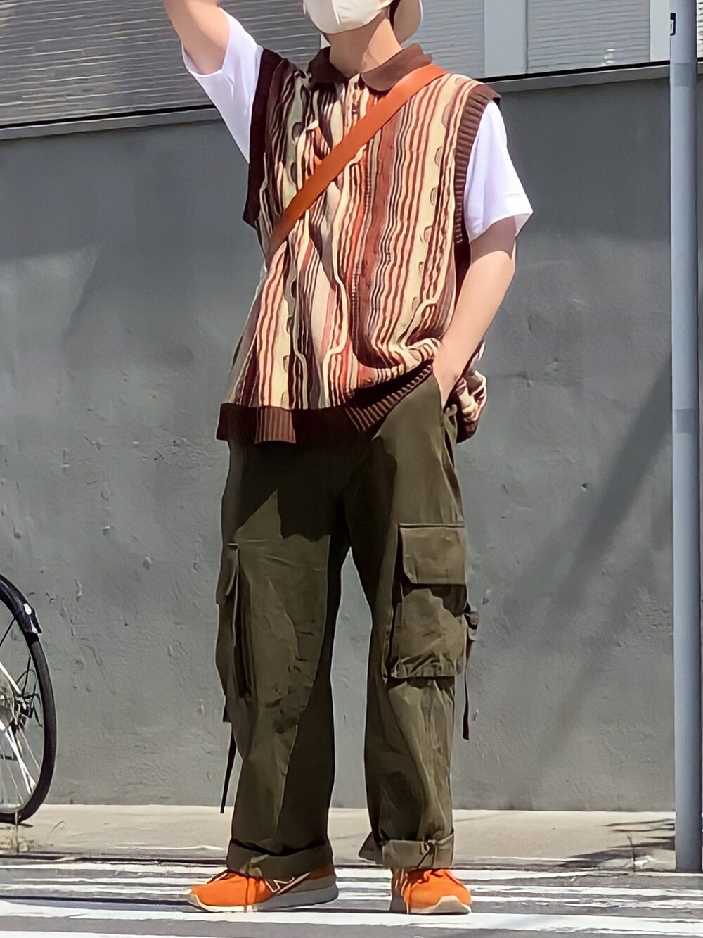 グリーン系のカーゴパンツ、ブラウン系のニット/セーター、ベージュ系のショルダーバッグを着用したメンズの秋コーディネートの2枚目の写真