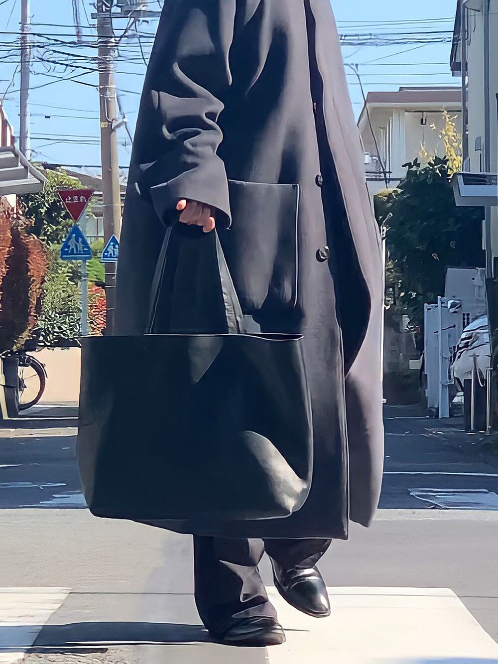 グレー系のステンカラーコート、ブラック系のトートバッグ、ブラック系のその他シューズを着用したメンズの秋コーディネートの2枚目の写真