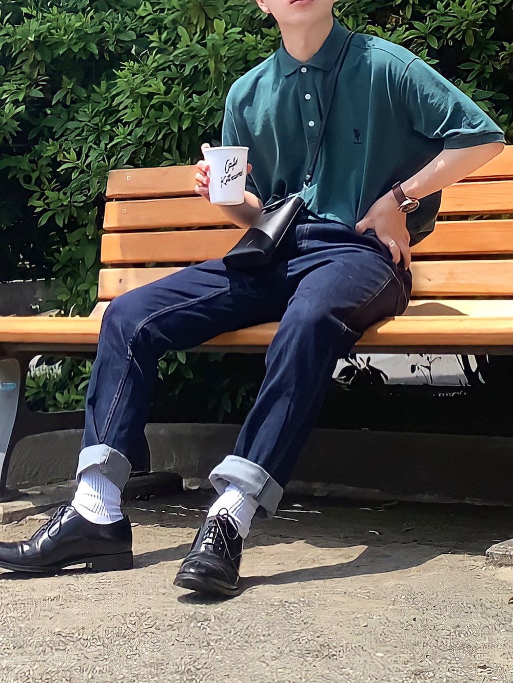 グリーン系のポロシャツ、ブルー系のデニムパンツ、ブラック系のショルダーバッグを着用したメンズの夏コーディネートの2枚目の写真