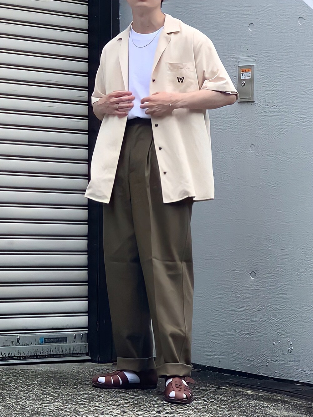 ブラウン系のサンダル、ベージュ系のシャツ/ブラウス、グリーン系のチノパンツを着用したメンズの春コーディネートの2枚目の写真