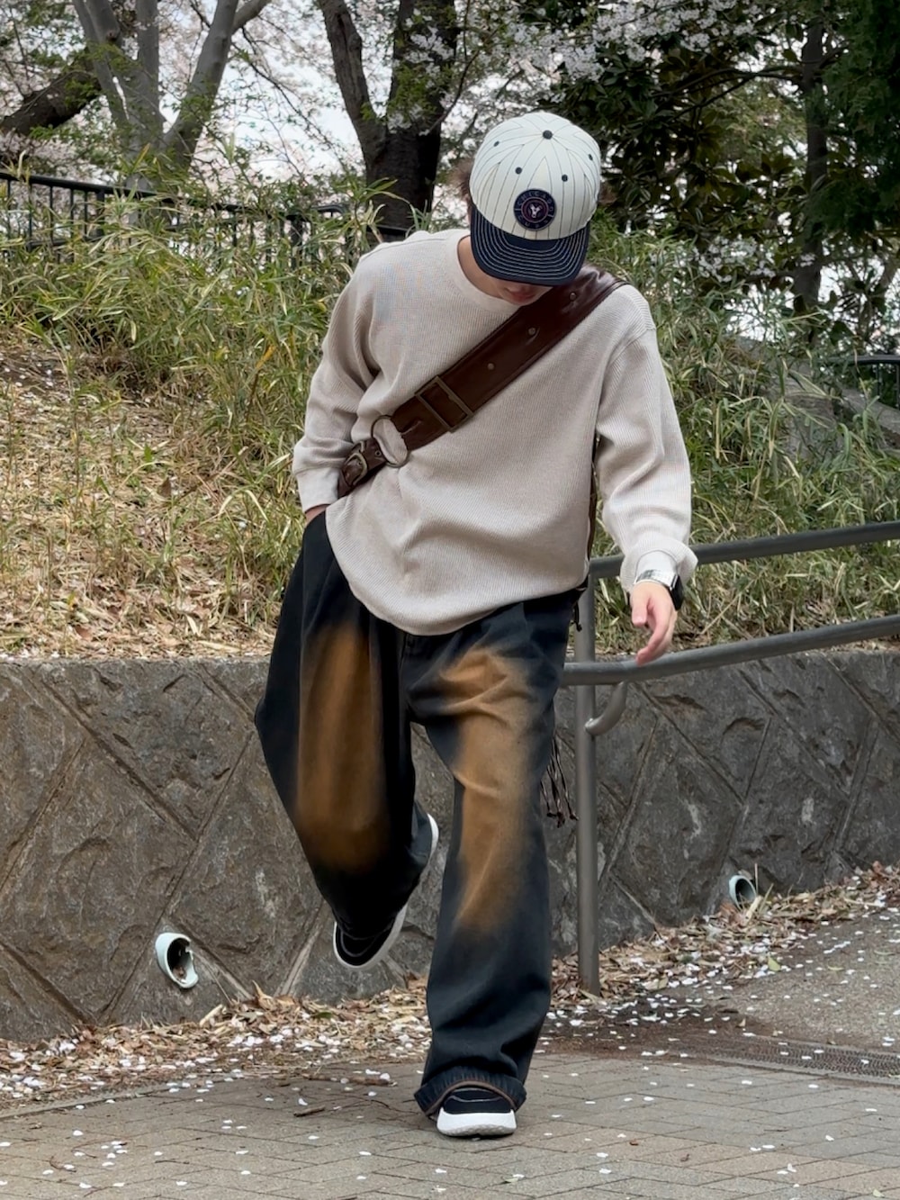 ブルー系のデニムパンツ、ベージュ系のTシャツ/カットソー、ブラウン系のショルダーバッグを着用したメンズの春コーディネートの3枚目の写真