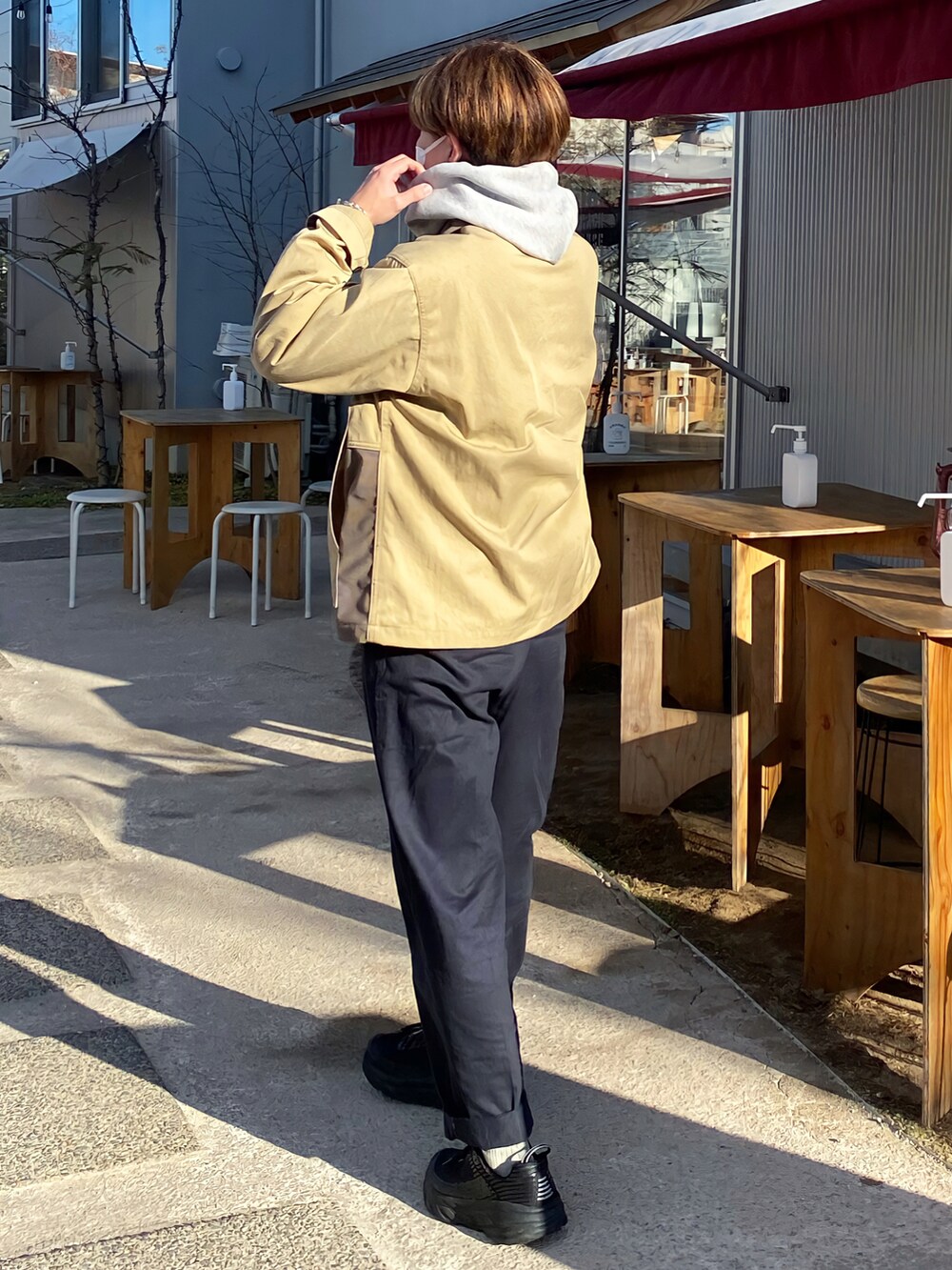 ベージュ系のノーカラージャケット、グレー系のパーカー、ブルー系のチノパンツを着用したメンズの冬コーディネートの2枚目の写真