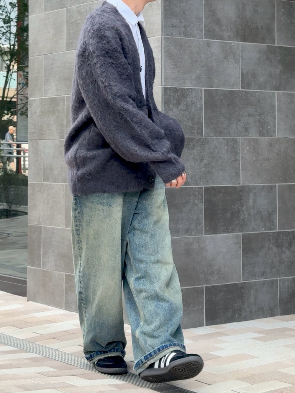 ブラック系のカーディガン/ボレロ、ブルー系のデニムパンツ、ブラック系のスニーカーを着用したメンズの秋コーディネートの2枚目の写真