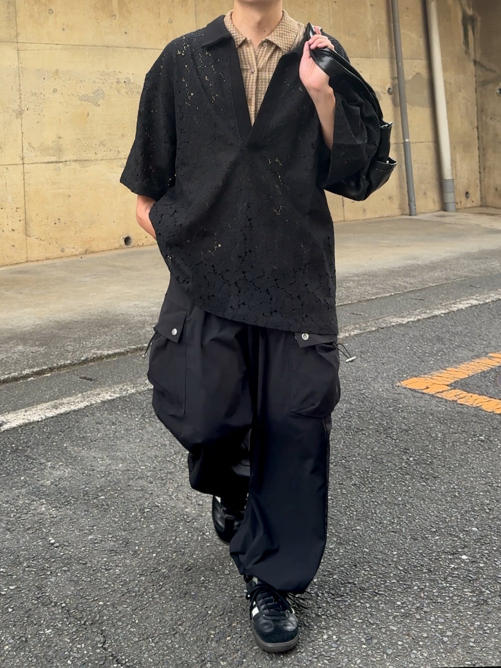 ブラック系のカーゴパンツ、ブラック系のポロシャツ、ブラック系のスニーカーを着用したメンズの秋コーディネートの3枚目の写真