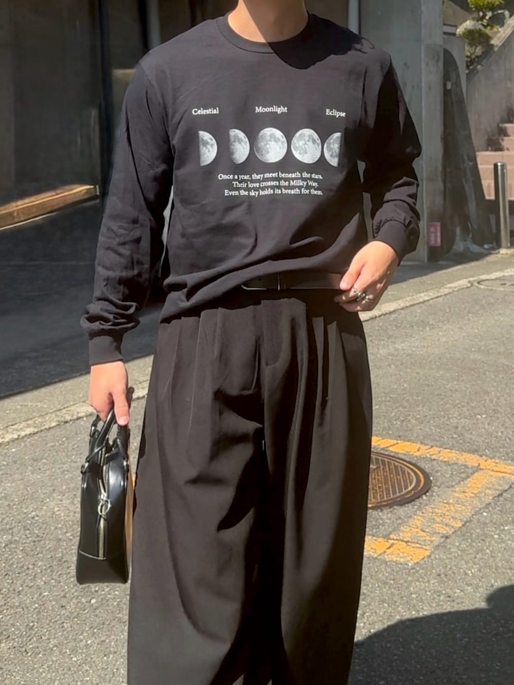ブラック系のスラックス、ブラック系のスニーカー、ブラック系のTシャツ/カットソーを着用したメンズの秋コーディネートの2枚目の写真