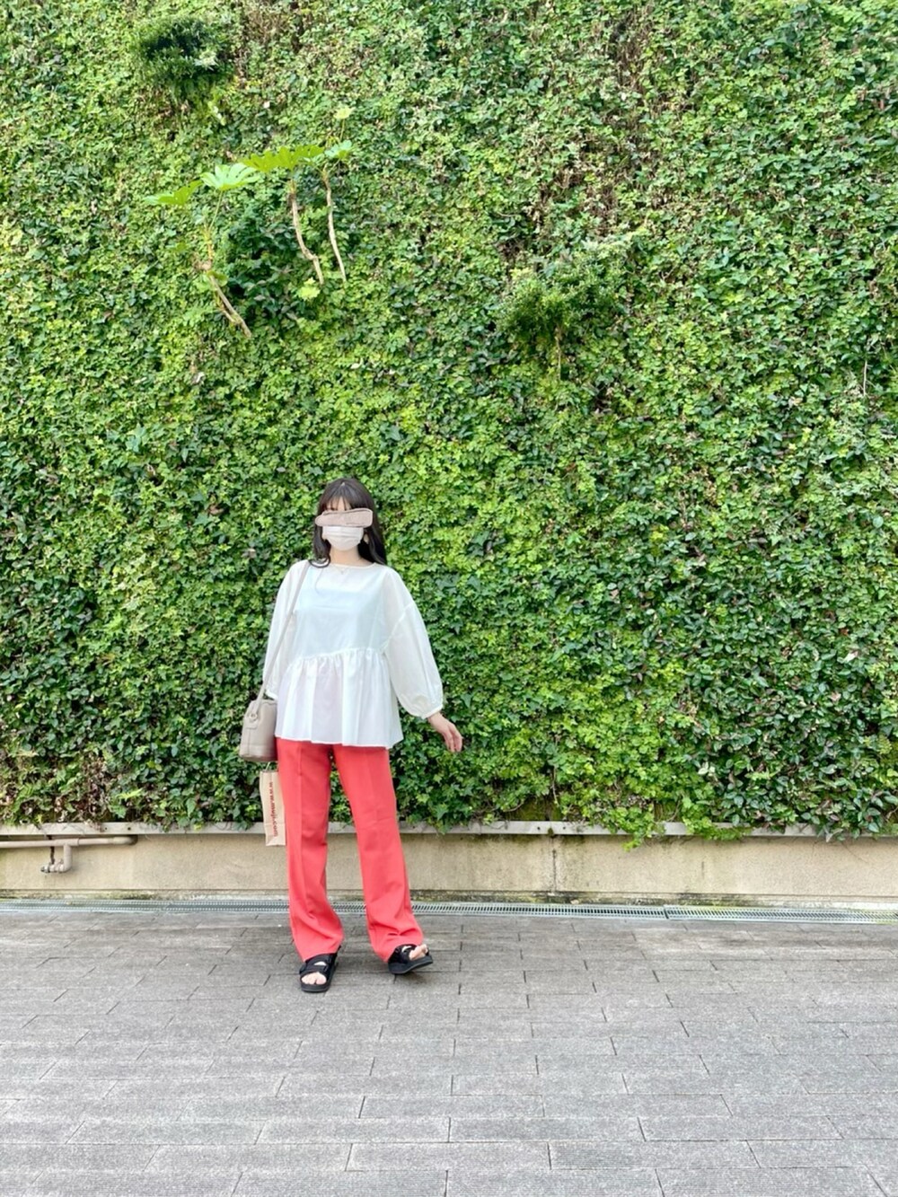 オレンジ系のスラックス、ホワイト系のシャツ/ブラウス、ベージュ系のショルダーバッグを着用したレディースの夏コーディネートの2枚目の写真