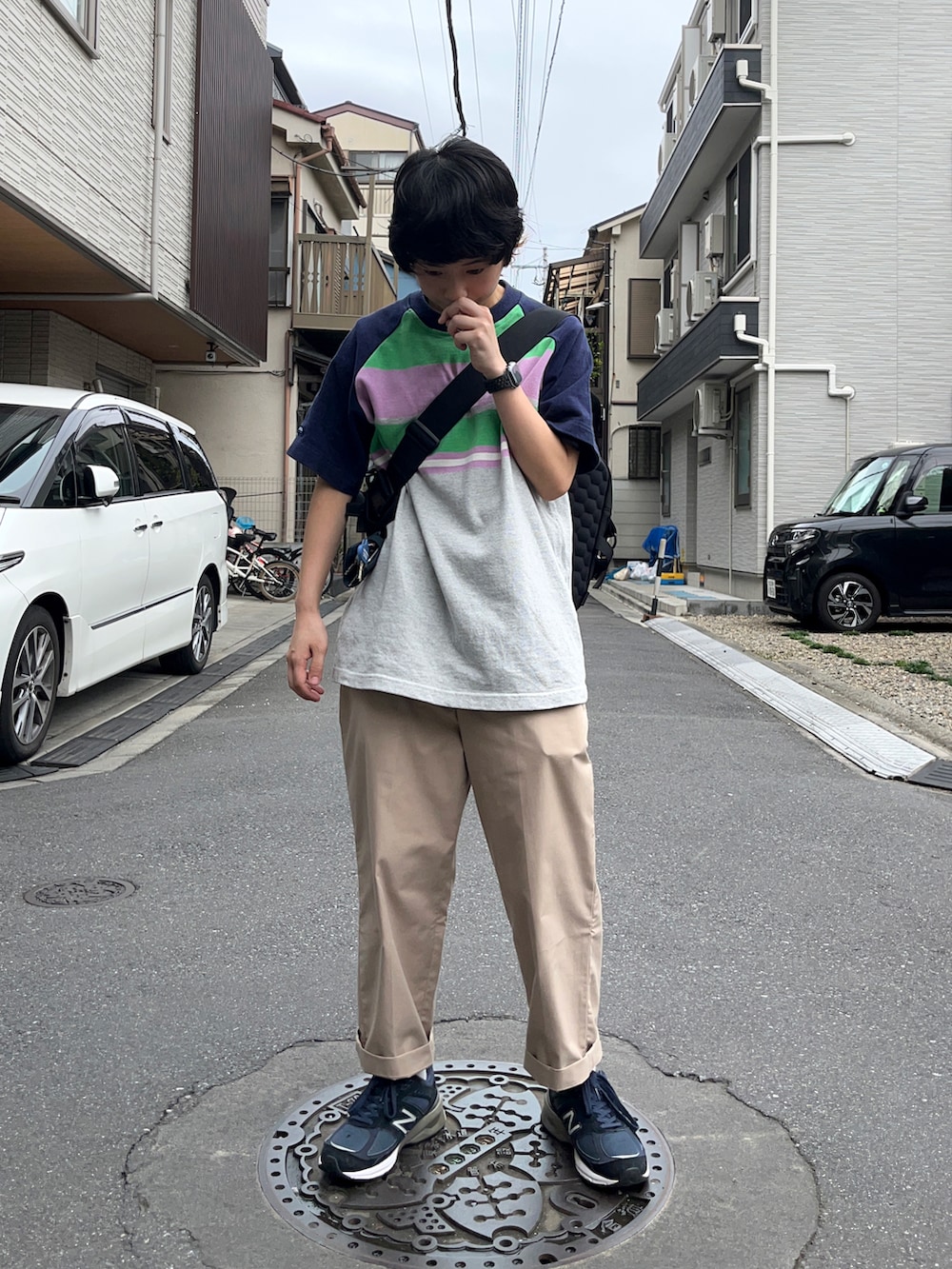 ベージュ系のチノパンツ、ブルー系のスニーカー、ブラック系のショルダーバッグを着用したレディースの秋コーディネートの2枚目の写真