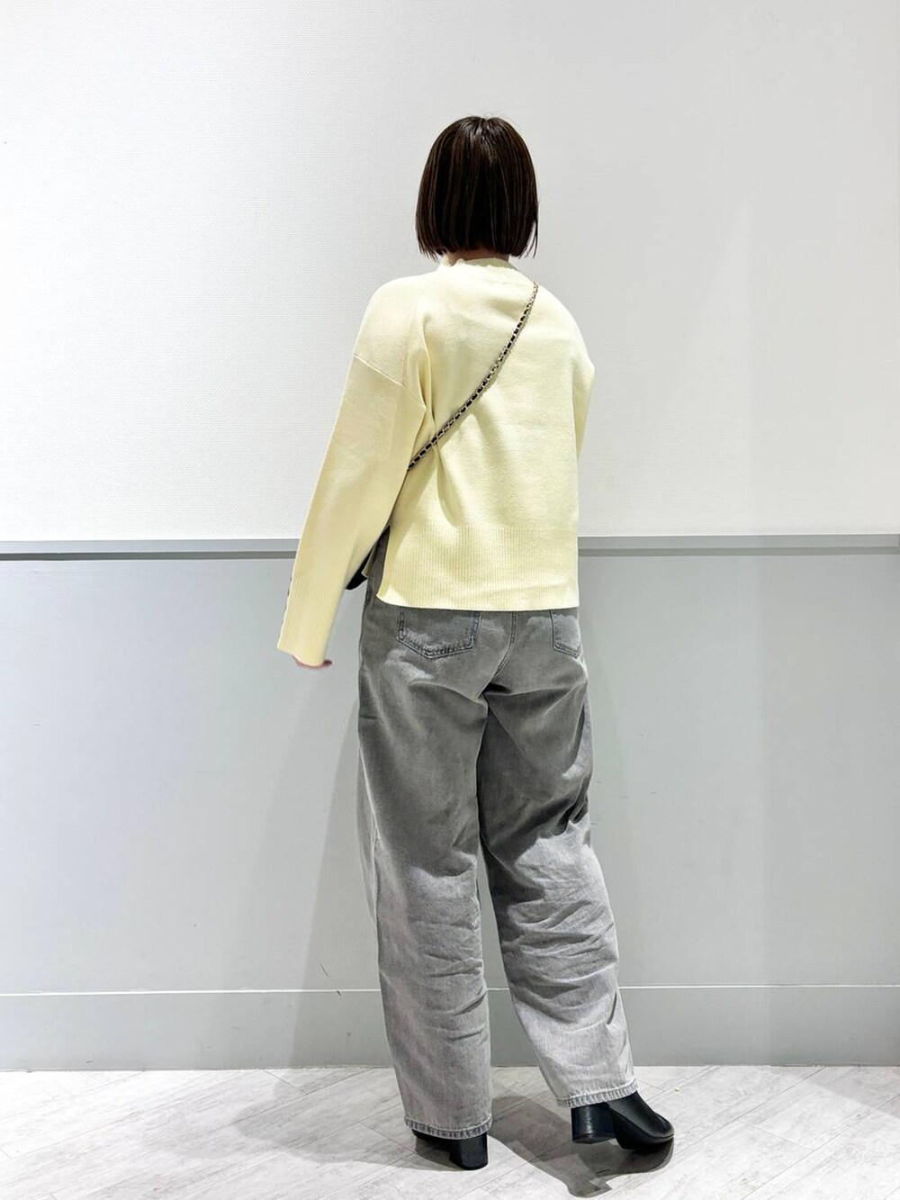 グレー系のデニムパンツ、ブラック系のブーツ、ブラック系のショルダーバッグを着用したレディースの冬コーディネートの3枚目の写真