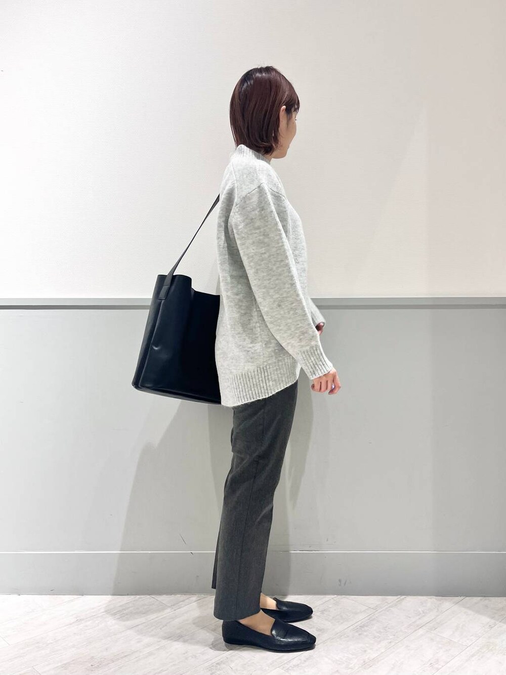 ブラック系のパンプス、グレー系のニット/セーター、ブラック系のショルダーバッグを着用したレディースの冬コーディネートの4枚目の写真