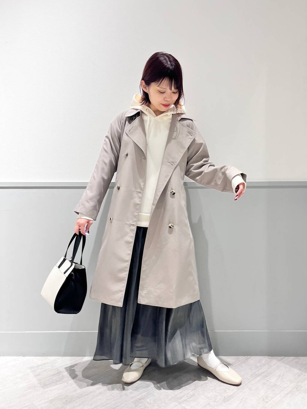 ホワイト系のパンプス、その他のショルダーバッグ、ブラック系のスカートを着用したレディースの冬コーディネートの2枚目の写真
