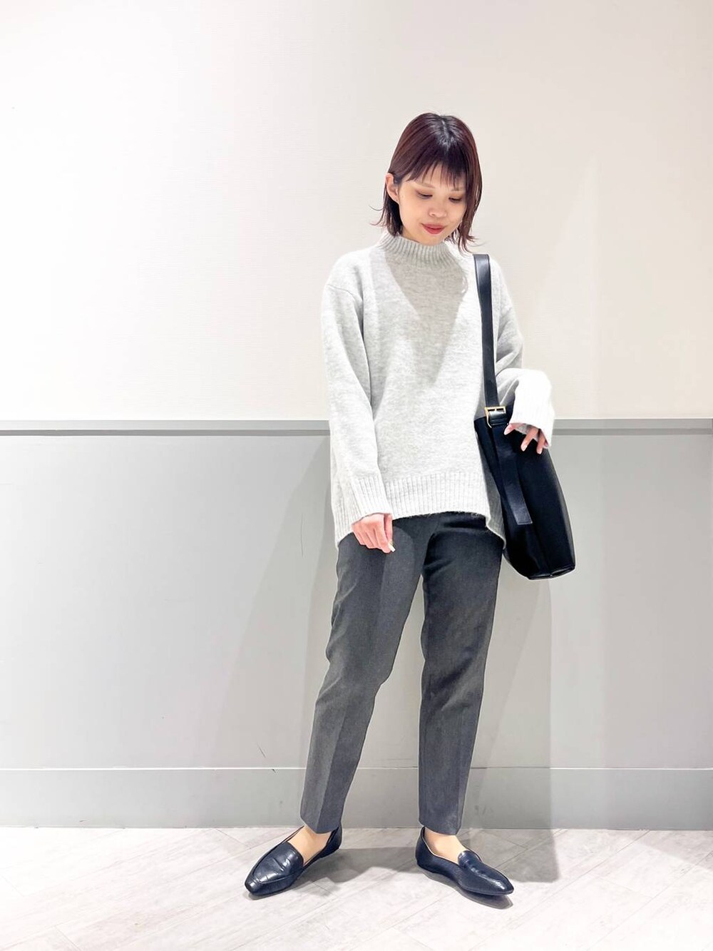 ブラック系のパンプス、グレー系のニット/セーター、ブラック系のショルダーバッグを着用したレディースの冬コーディネートの2枚目の写真