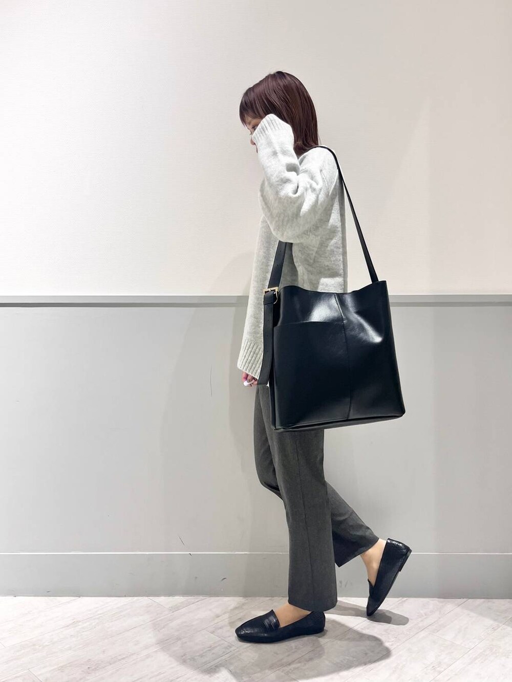 ブラック系のパンプス、グレー系のニット/セーター、ブラック系のショルダーバッグを着用したレディースの冬コーディネートの6枚目の写真