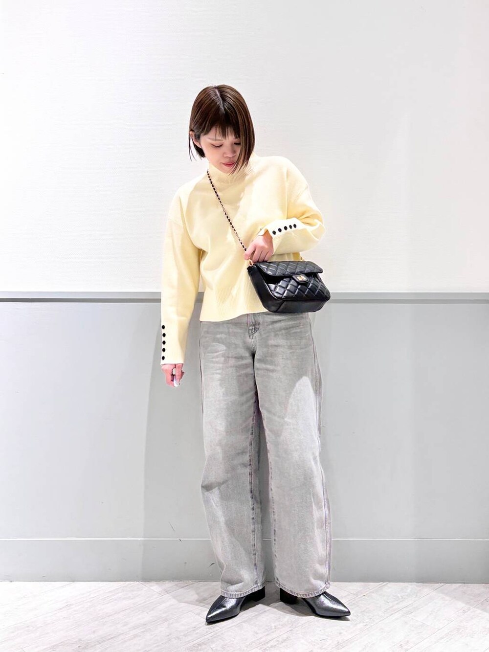 グレー系のデニムパンツ、ブラック系のブーツ、ブラック系のショルダーバッグを着用したレディースの冬コーディネートの2枚目の写真