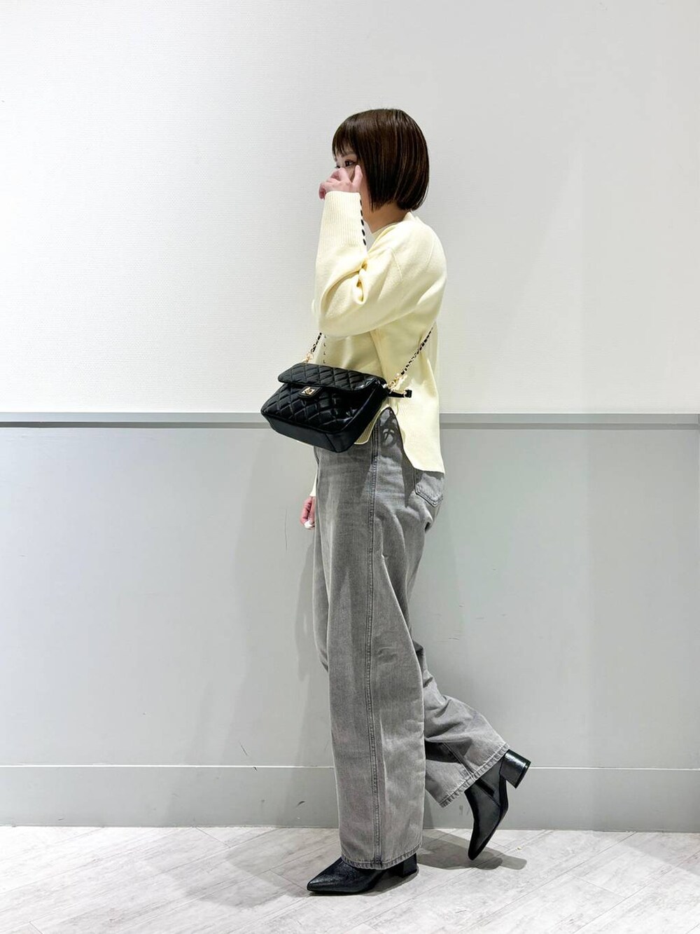 グレー系のデニムパンツ、ブラック系のブーツ、ブラック系のショルダーバッグを着用したレディースの冬コーディネートの4枚目の写真