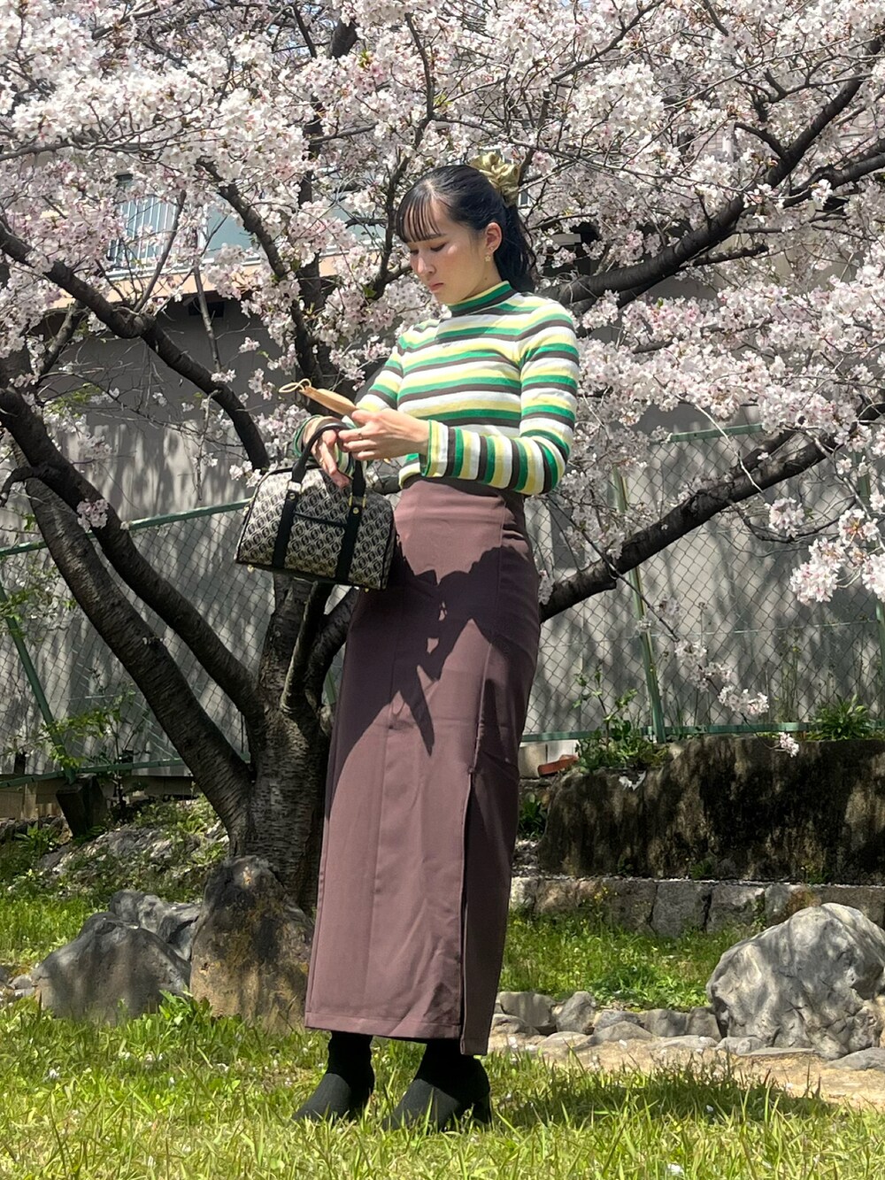 グリーン系のトップス、ブラウン系のスカートを着用したレディースの春コーディネートの2枚目の写真