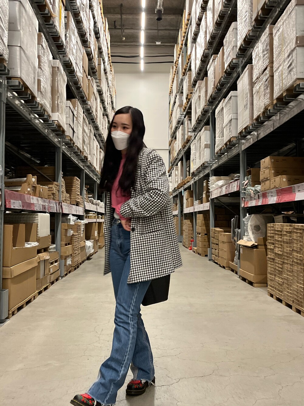 ブルー系のデニムパンツ、ブラック系のブーツ、ブラック系のハンドバッグを着用したレディースの春コーディネートの3枚目の写真