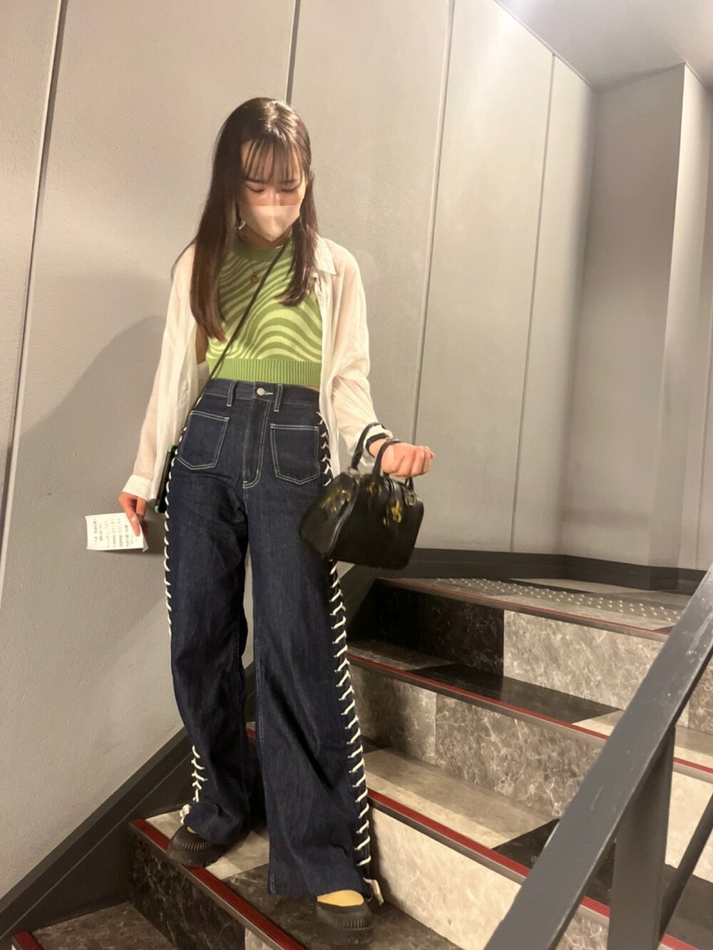 ブルー系のデニムパンツ、ベージュ系のスニーカー、ブラック系のバッグを着用したレディースの夏コーディネートの2枚目の写真