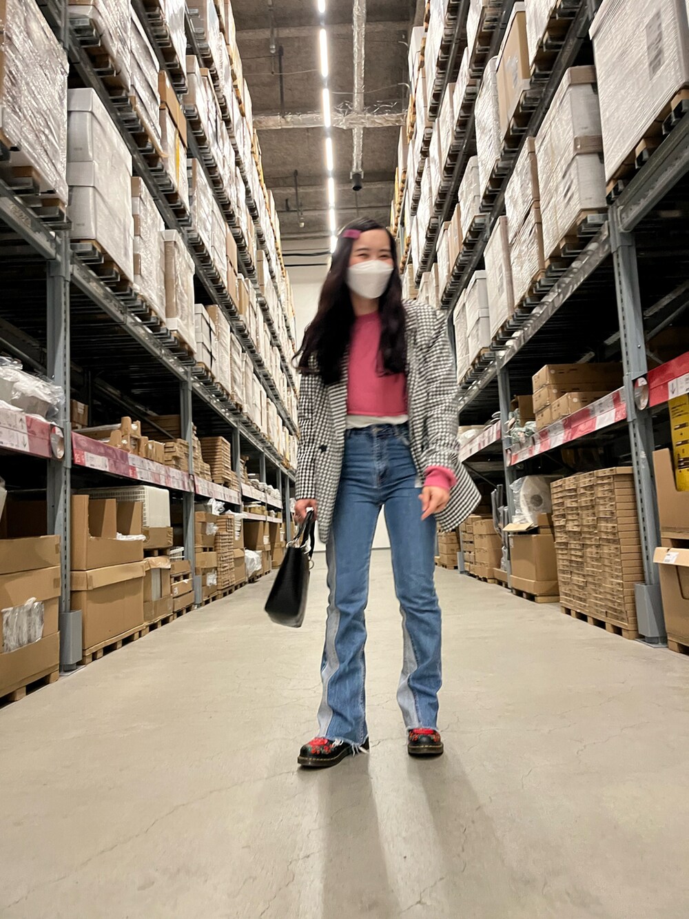 ブルー系のデニムパンツ、ブラック系のブーツ、ブラック系のハンドバッグを着用したレディースの春コーディネートの2枚目の写真