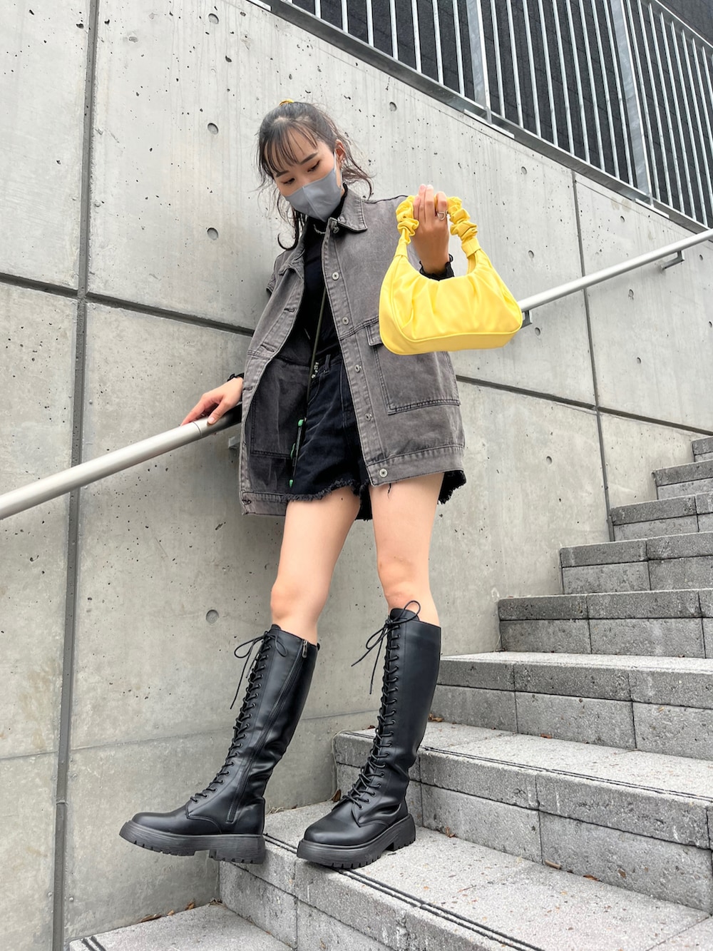 ブラック系のブーツ、ブラック系のデニムジャケット、イエロー系のハンドバッグを着用したレディースの秋コーディネートの2枚目の写真