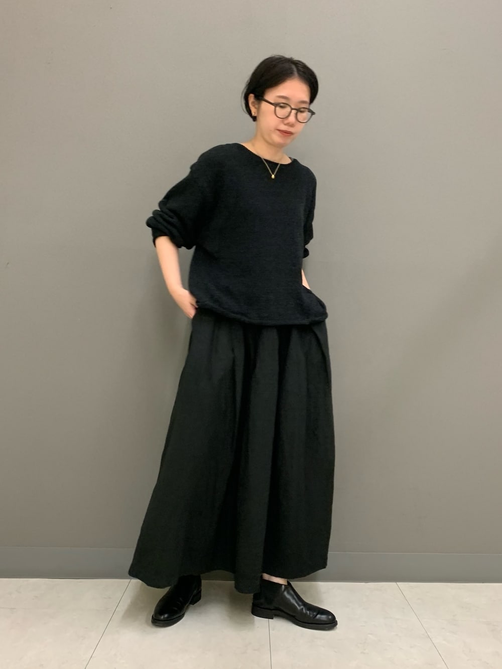 ブラック系のスカート、ブラック系のニット/セーター、ブラック系のブーツを着用したレディースの秋コーディネートの4枚目の写真