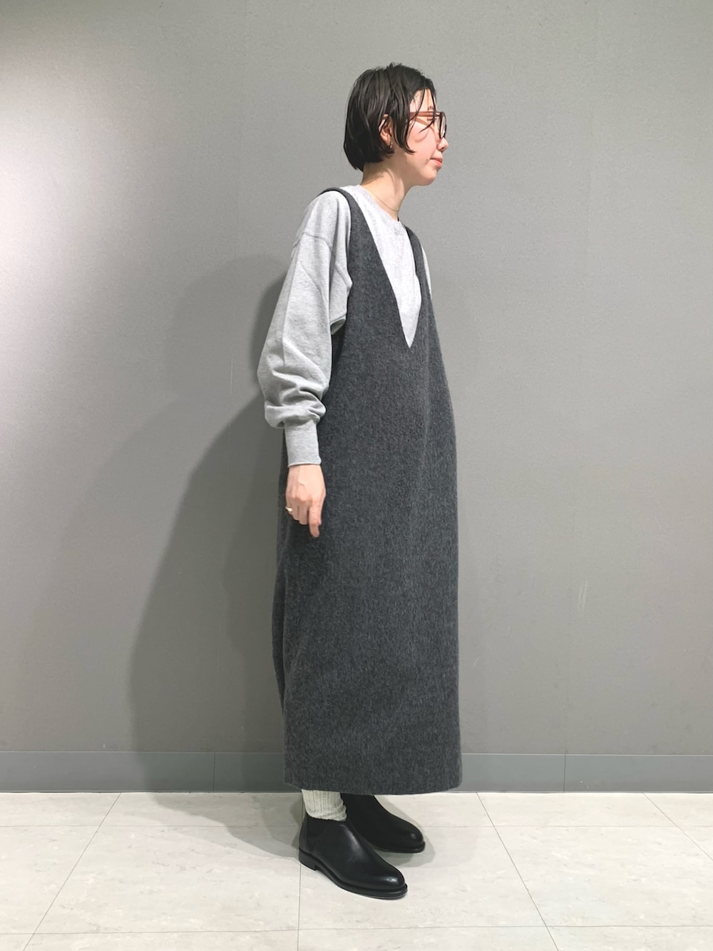 グレー系のTシャツ/カットソー、グレー系のワンピース、ブラック系のブーツを着用したレディースの秋コーディネートの3枚目の写真