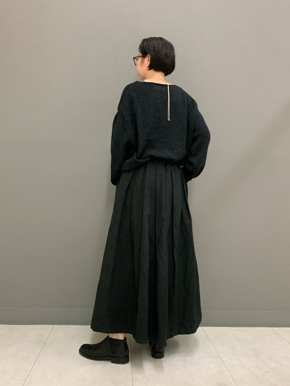 ブラック系のスカート、ブラック系のニット/セーター、ブラック系のブーツを着用したレディースの秋コーディネートの3枚目の写真